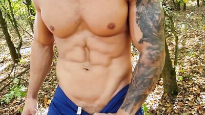 Dashing bodybuilder flexes his big muscles in nature and jerks off