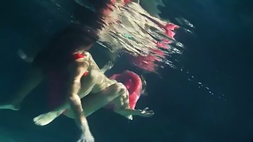 Lesbians are slowly taking off their clothes in the swimming pool and touching each other