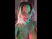 Smiling with neon light glowing on her bare shoulders 🤤