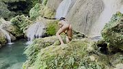 Monika Foxxx in yellow swimsuit against backdrop of waterfalls