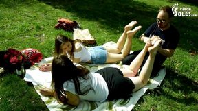 Two barefoot girls in park having their feet worshiped by a stranger