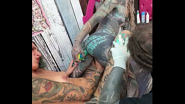 Petite lesbian gets inked and takes a huge dildo in her tight ass while in