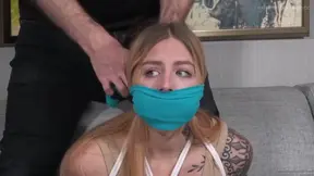 Tied blonde on grey couch gets gagged and bound in white rope for hardcore fetish play
