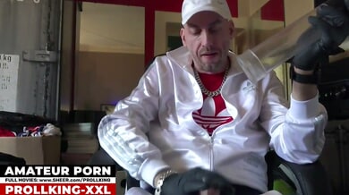 Man in cap and gloves tests a transparent device on his erect cock in a red-walled room