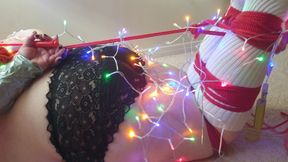 Miss K hogtied and wrapped in Christmas lights has socked feet tickled