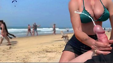 MILF gives a hand job and blowjobs on the beach leading to a public cum shot