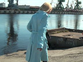 Blonde sweetie in blue raincoat undresses behind the car