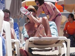 Topless hottie doesn't give a screw that everybody is staring at her melons, on the beach