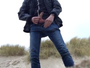 young man urinates in the dunes