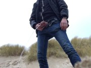 young man urinates in the dunes