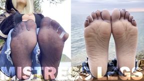 Feet in black and grey nylon socks wiggling toes at the seashore