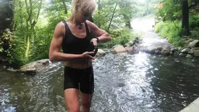 Alexa Cosmic trans girl swimming in font near waterfall wearing shorts and t-shirt...