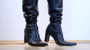 office girl standing in front of you in shiny pointed leather boots toe and heel tapping