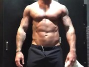 Fit tattooed man strips in gym locker room