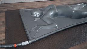 Slow and merciless relaxation of a girl on a gray latex vacuum bed