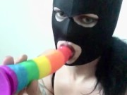 Transgender in mask sucking a rainbow dildo