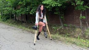 Girl on crutches, walking on crutches, broken leg, pulled ligaments, cast on leg, girl walking down the street on crutches and heels