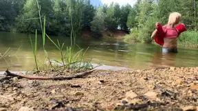 Trans-girl swimming in jeans and pink top in the lake..