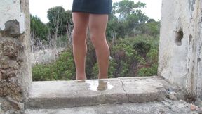 A sissy in stockings, high heels and a chastity belt pees over a small penis
