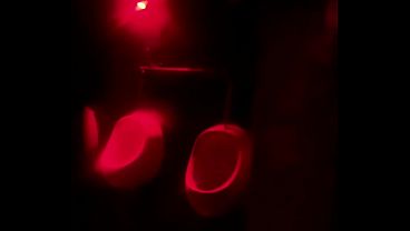 Amateur boy lending hand to his friend pissing in public toilets'_ urinal