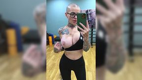 Bald headed MILF with tattooed body masturbates pussy in the gym