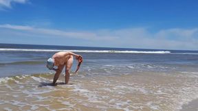 Amateur filming. A nudist plays with waves on the ocean shore.