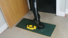 Nikkichick crushes a yellow street race car in big stiletto boots and dangles it on her heel right view