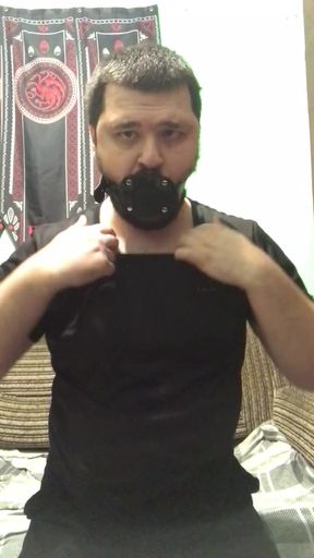 A man puts a gag in his mouth and an anal plug