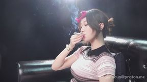 Asian Woman Smoking Cigarette Blowing Thick Smoke Rings and Deep Inhales on Leather Couch — QI1 HD