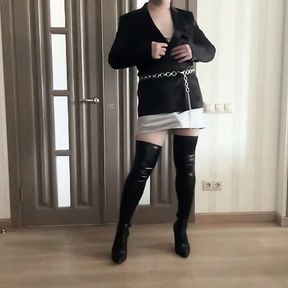 Sissy cuckold crossdresser in satin jacket, silk mini dress, high heels overknee boots dancing and playing with a cock