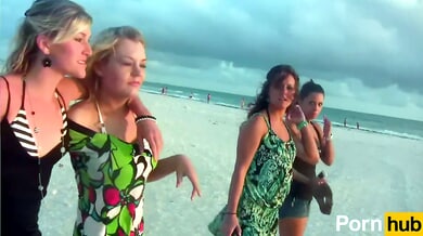 Two tan brunette women playfully expose themselves on a quiet beach