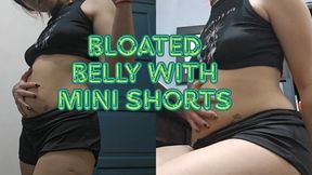 Bloated belly in black mini shorts and top, standing and sitting down with soft slaps
