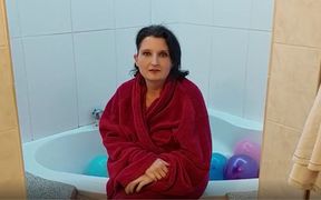 Mature brunette in the bathtub full of balloons