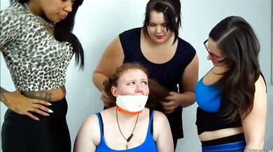 Red-haired woman subdued and gagged by three dominant women in a white room