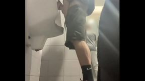 2 boys in sneakers having fun at public toilets'_ urinal